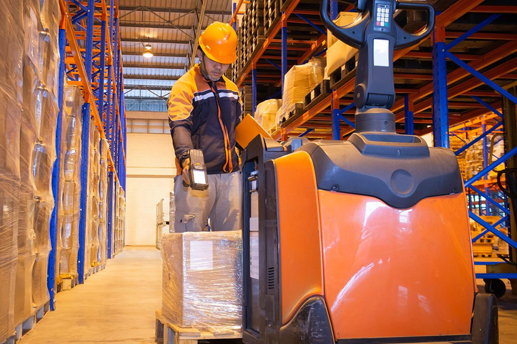 A worker scans the code of a palleted cargo in a warehouse