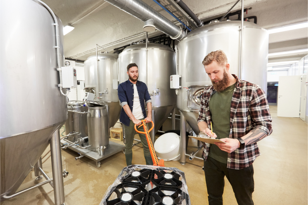 Two brewery owners prep a skid with kegs to be shipped