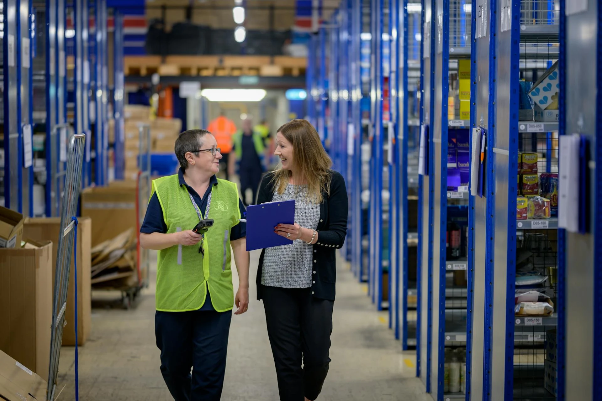 Warehouse manager wearing green safety vests inside a warehouse