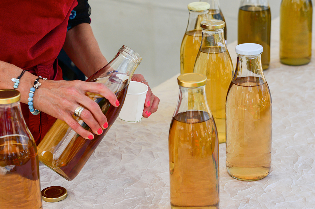  A woman pouring a sample of kombucha tea into a cup 