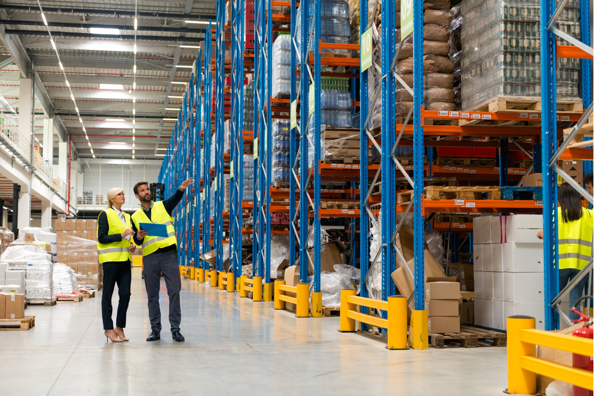 Warehouse managers wearing green safety vests inside a warehouse