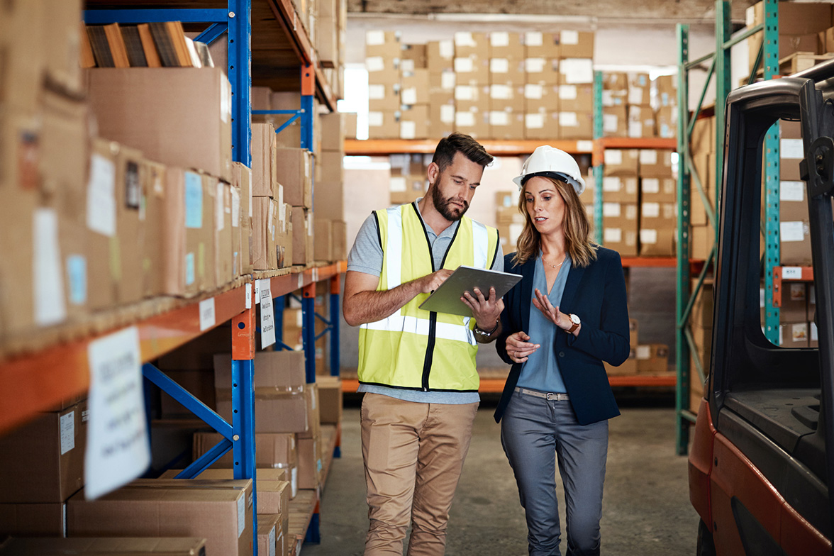 Two people discussing LTL and parcel shipping logistics inside a warehouse