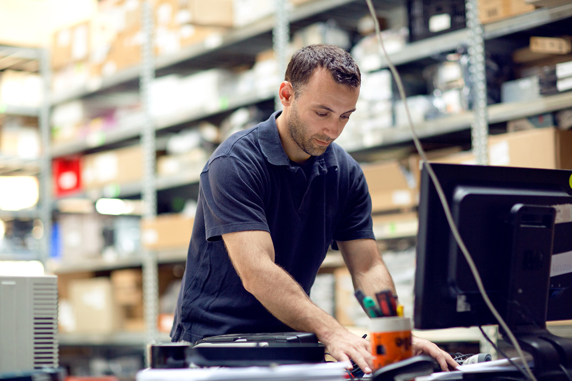 Business owner using a computer in a warehouse to vet new carrier partners