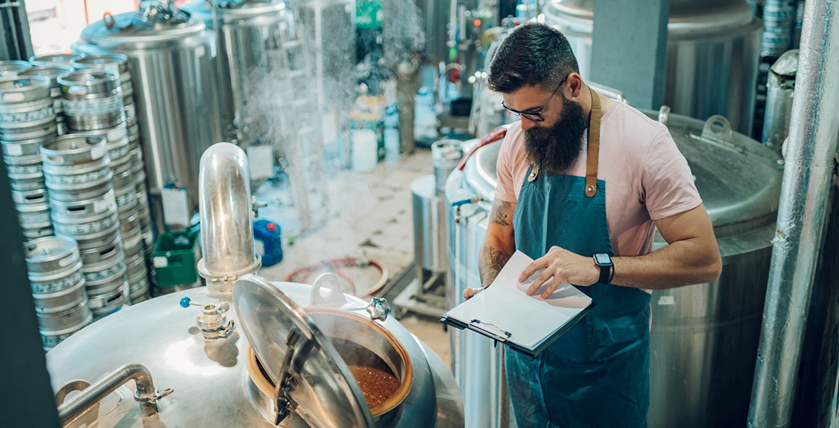 A beverage startup owner conducting quality control at a brewery