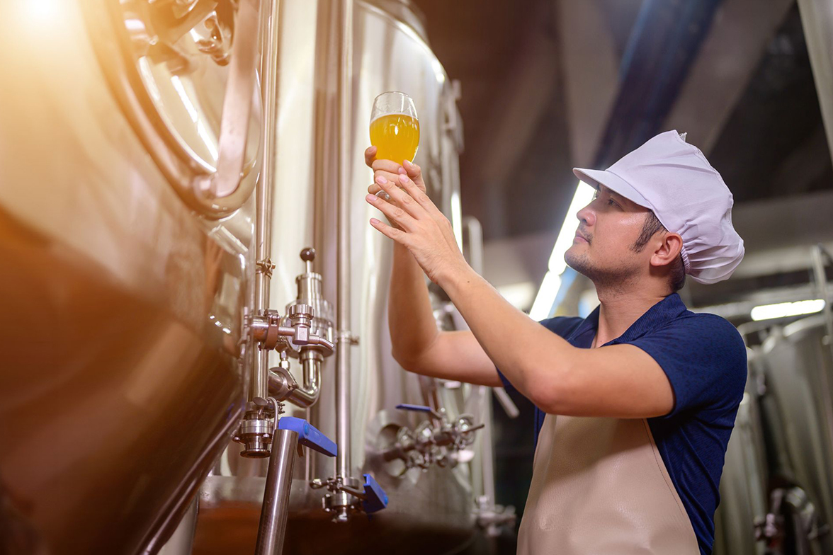 A beverage company employee holding a beer glass in his hand and inspecting craft beer
