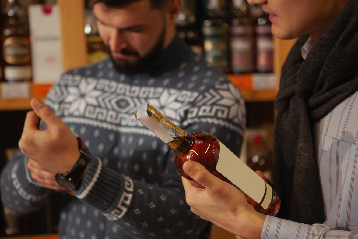 Consumers read the labels on their alcohol bottles in a store setting.