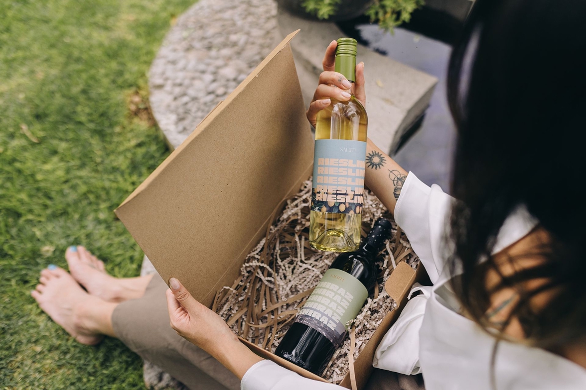 A woman checking a pair of wine bottles from a wine subscription box