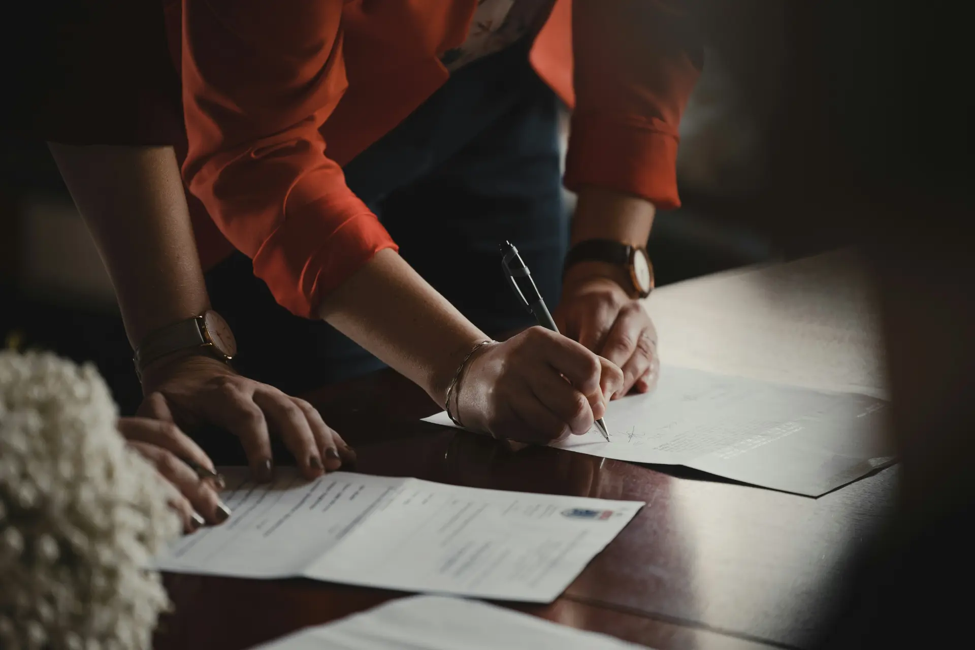 a woman signing a document on a desk