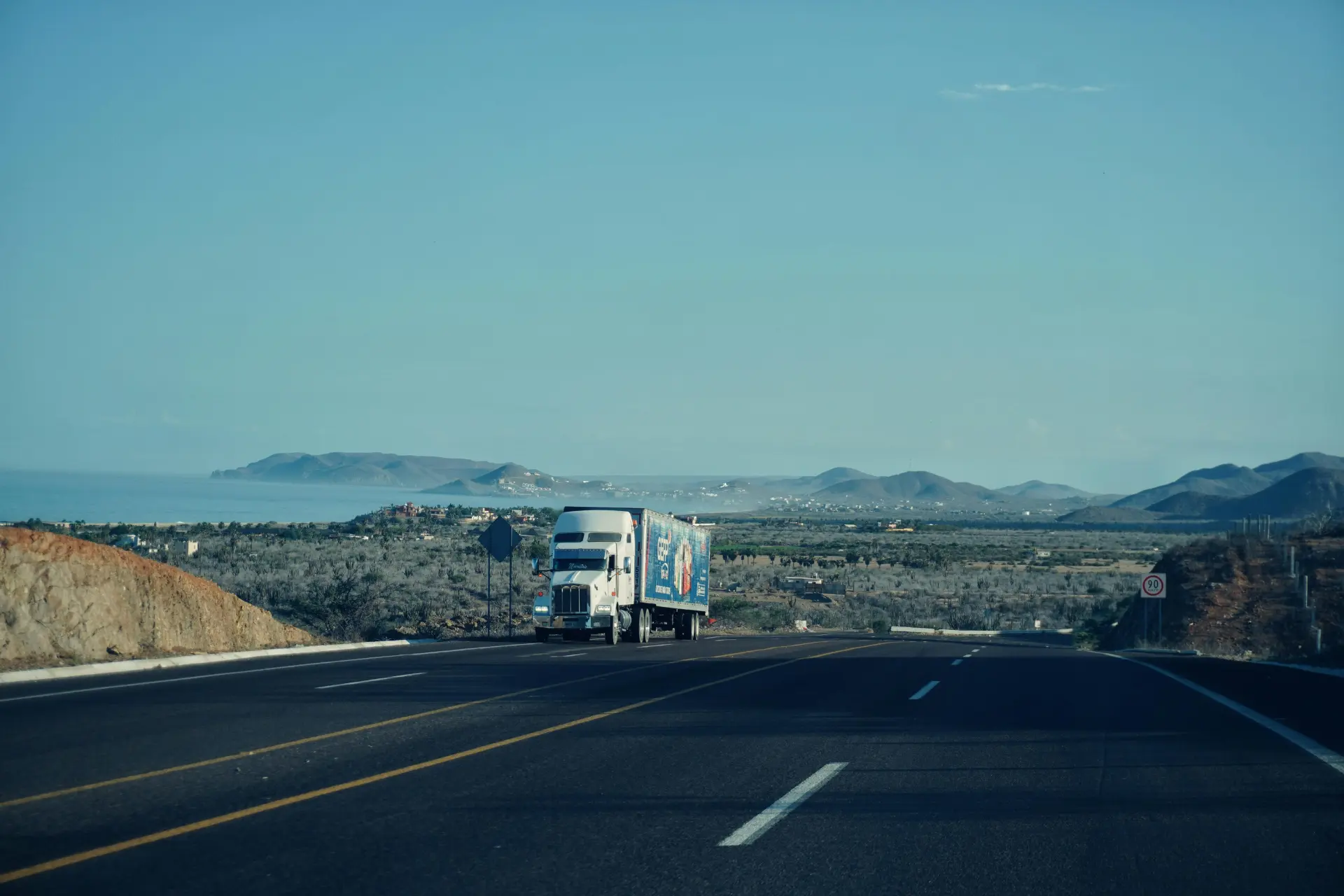 semi-trick on a scenic highway with mountains in the background 