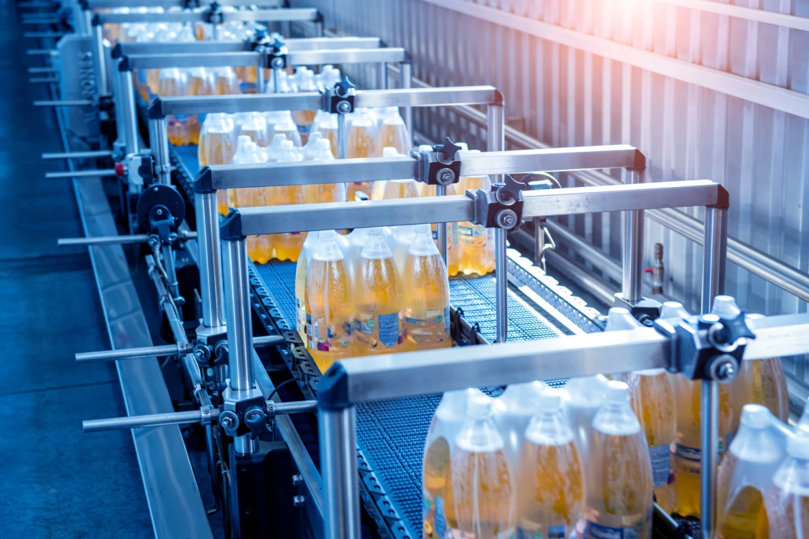 Packaged bottles of beverages are transported via a modern strapping machine at a packaging facility