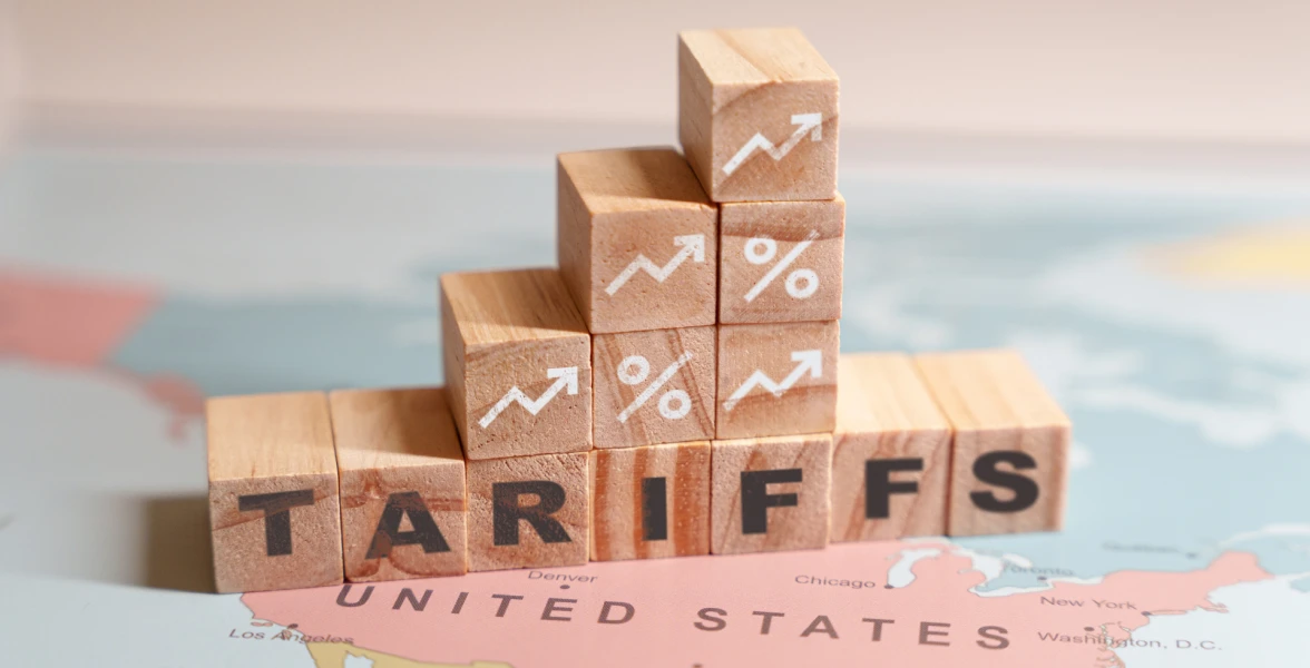 Wooden blocks spelling TARIFFS are placed on a map of North America, specifically over the United States
